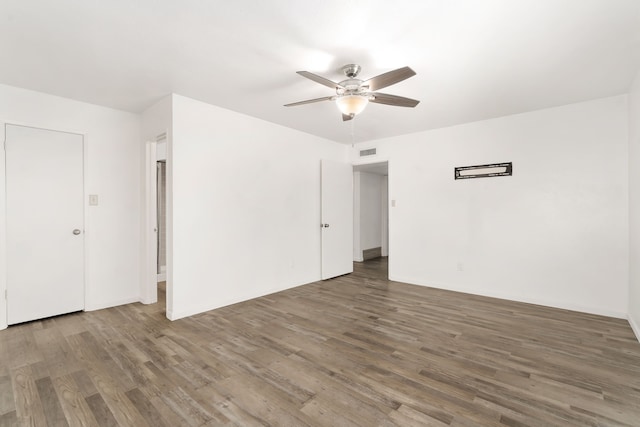 unfurnished room with wood finished floors, visible vents, and a ceiling fan