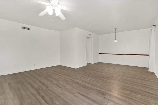 unfurnished room featuring ceiling fan, wood finished floors, visible vents, and baseboards