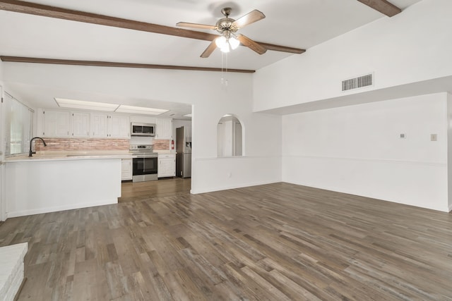 unfurnished living room with vaulted ceiling with beams, a sink, visible vents, a ceiling fan, and dark wood-style floors