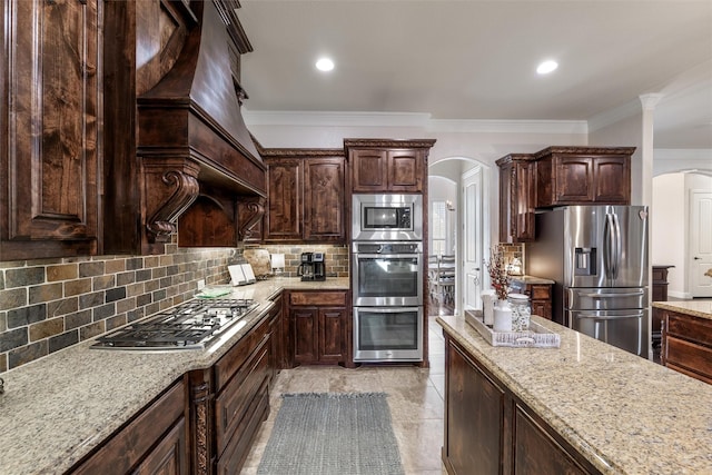 kitchen with arched walkways, crown molding, stainless steel appliances, backsplash, and dark brown cabinets