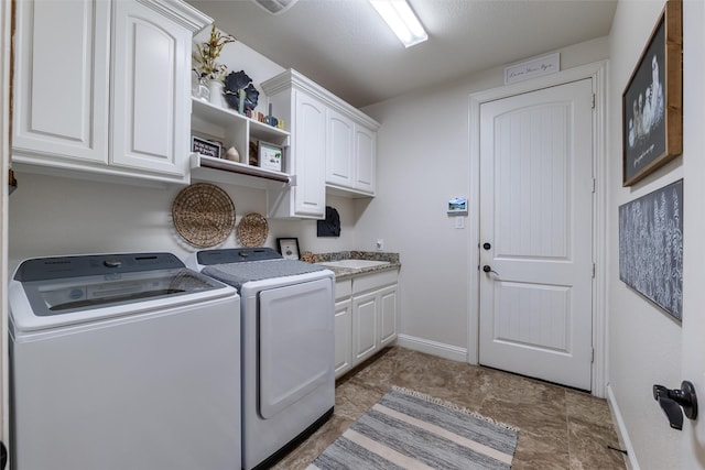 clothes washing area featuring separate washer and dryer, cabinet space, and baseboards