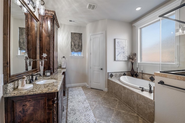 bathroom with vanity, a garden tub, visible vents, and baseboards