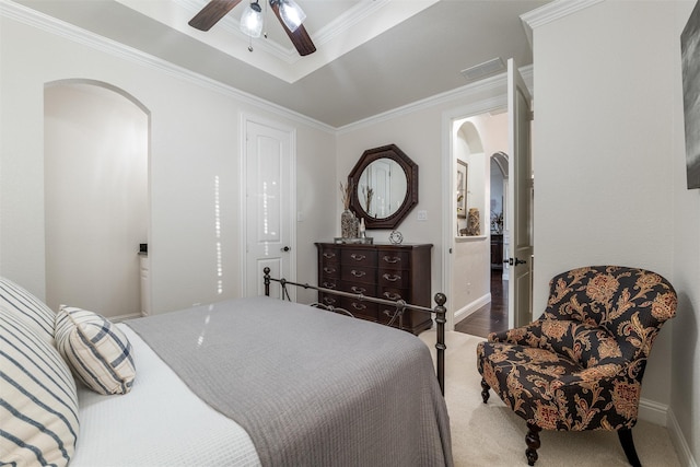 carpeted bedroom with arched walkways, ceiling fan, visible vents, a raised ceiling, and crown molding