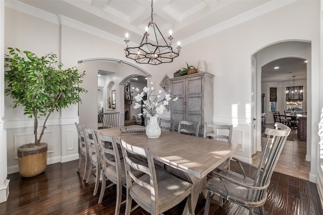 dining room with arched walkways, coffered ceiling, dark wood-type flooring, a chandelier, and a decorative wall