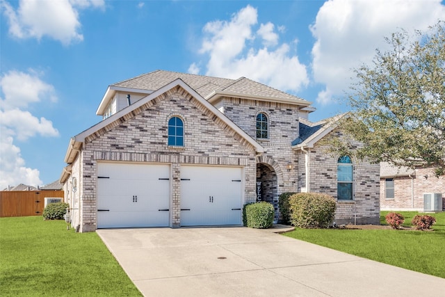 french country style house featuring an attached garage, cooling unit, brick siding, driveway, and a front lawn