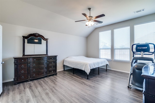 bedroom with light wood-type flooring, visible vents, vaulted ceiling, and baseboards