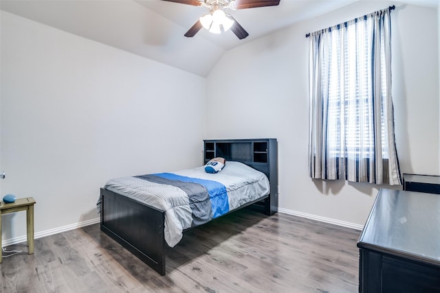 bedroom with a ceiling fan, lofted ceiling, baseboards, and wood finished floors