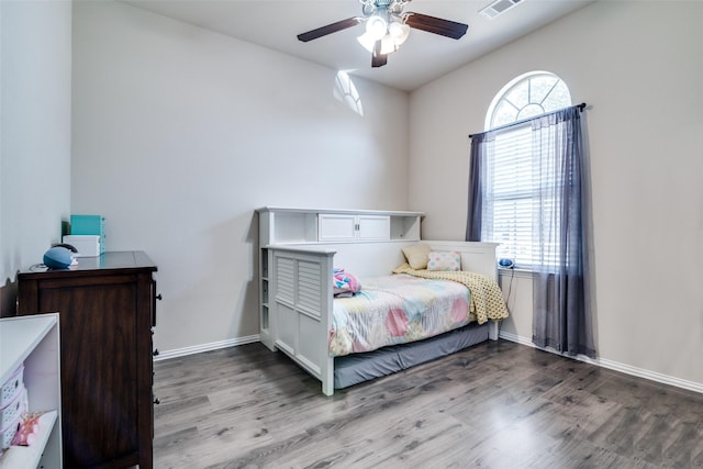 bedroom featuring a ceiling fan, multiple windows, baseboards, and wood finished floors