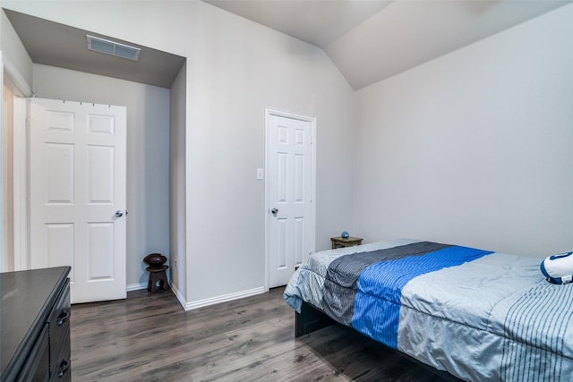 bedroom featuring dark wood finished floors, visible vents, vaulted ceiling, and baseboards