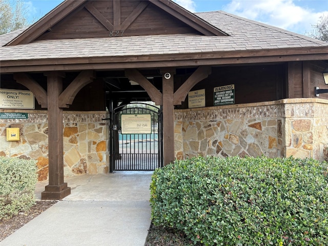 doorway to property featuring a shingled roof and stone siding