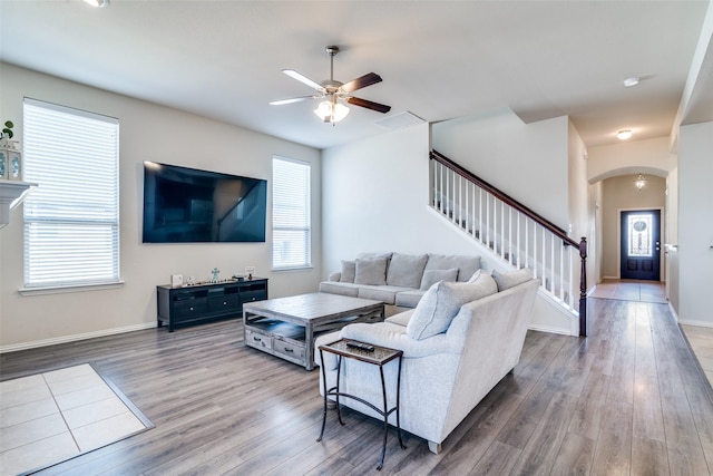 living room featuring arched walkways, wood finished floors, visible vents, baseboards, and stairs