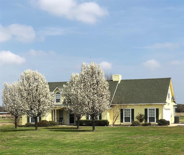 view of front of house featuring a front lawn and a shingled roof