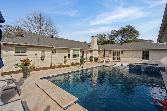 view of swimming pool featuring french doors, a patio area, and a pool with connected hot tub