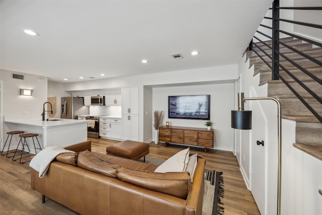 living area with recessed lighting, visible vents, baseboards, and wood finished floors