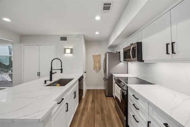 kitchen with stainless steel appliances, a peninsula, a sink, and visible vents