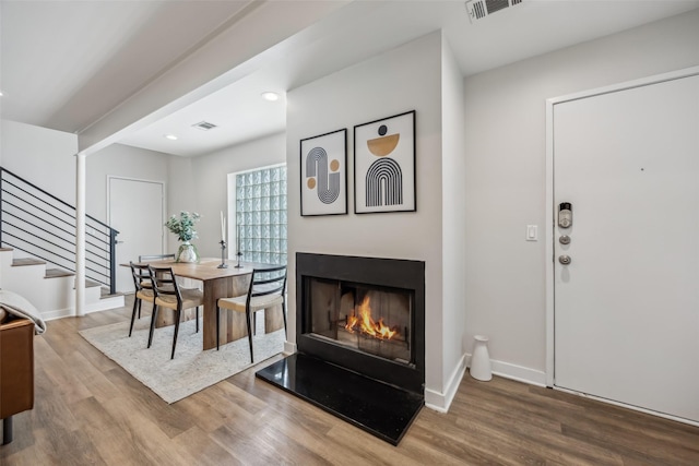 dining space with stairs, wood finished floors, visible vents, and baseboards