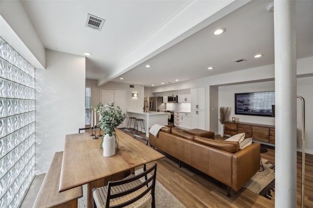 dining space featuring visible vents, wood finished floors, beam ceiling, and recessed lighting