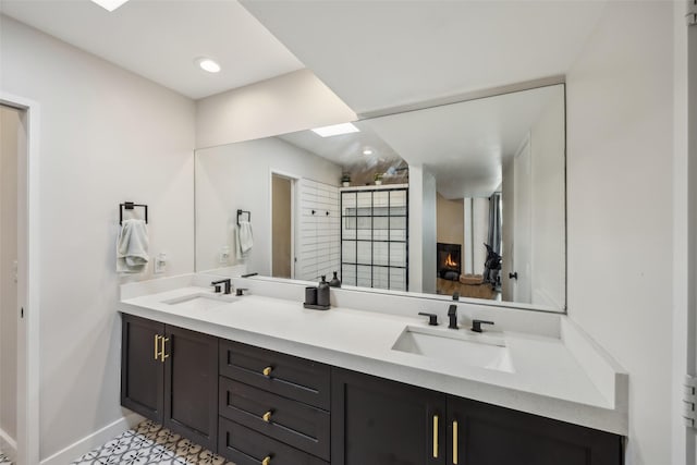 bathroom featuring double vanity, baseboards, walk in shower, and a sink