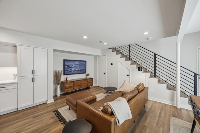 living area with recessed lighting, light wood-style flooring, and stairs