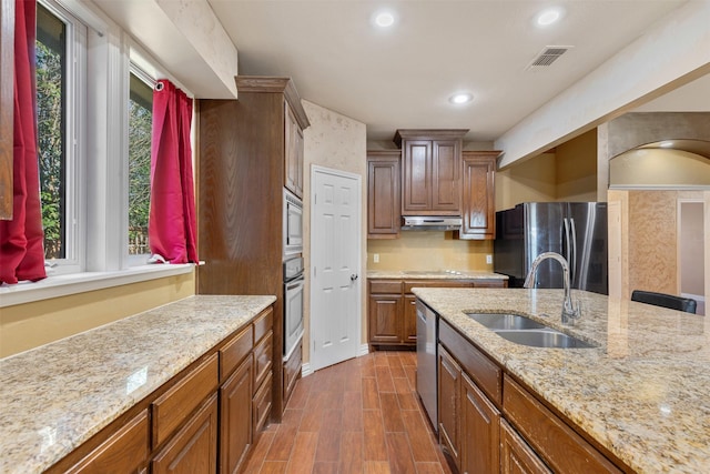 kitchen with under cabinet range hood, stainless steel appliances, dark wood-style flooring, a sink, and visible vents