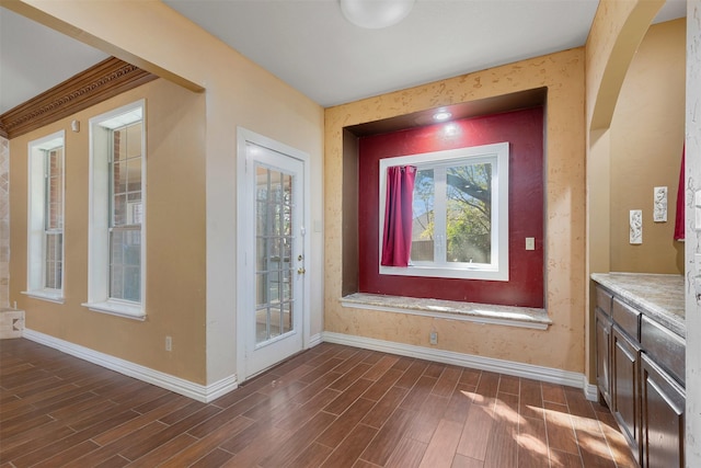 interior space with baseboards, arched walkways, and wood tiled floor