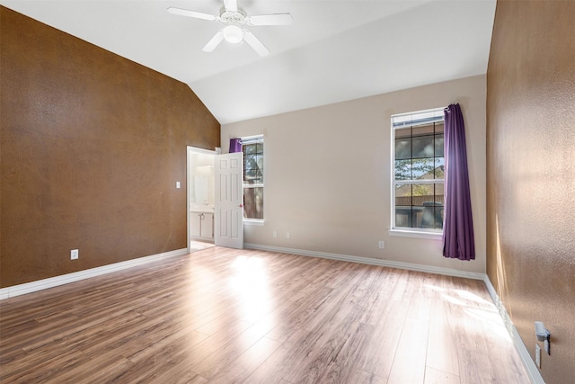 empty room with lofted ceiling, wood finished floors, a ceiling fan, and baseboards