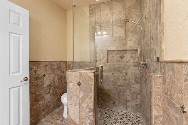 bathroom with tile patterned flooring, toilet, tile walls, wainscoting, and a shower stall