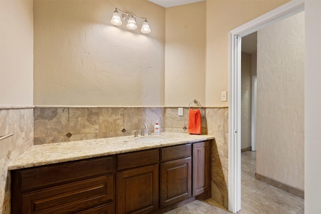 bathroom with a wainscoted wall, tile patterned flooring, vanity, and tile walls