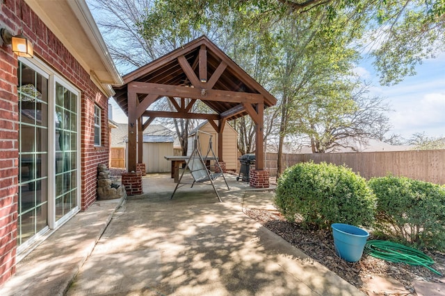 view of patio with fence private yard, an outdoor structure, a gazebo, and a storage shed