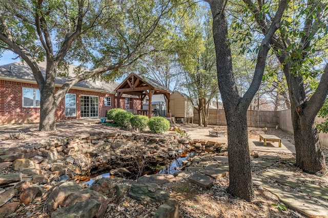 view of front facade featuring a patio, brick siding, and fence