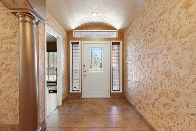 entrance foyer featuring light tile patterned floors, visible vents, baseboards, vaulted ceiling, and wallpapered walls