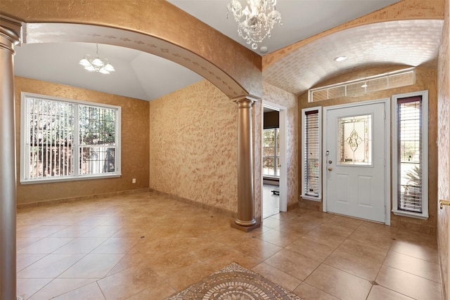 entryway with arched walkways, vaulted ceiling, a notable chandelier, and ornate columns