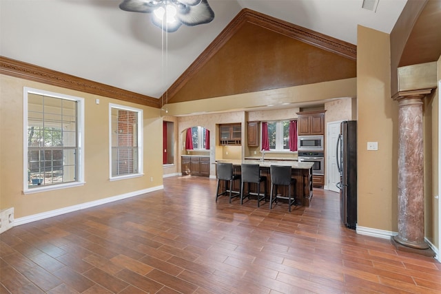 kitchen featuring a breakfast bar area, light countertops, appliances with stainless steel finishes, dark wood finished floors, and ornate columns