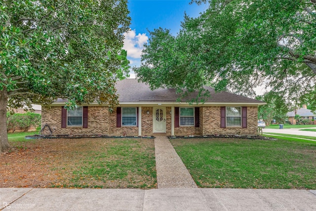 ranch-style house featuring brick siding, a shingled roof, and a front yard