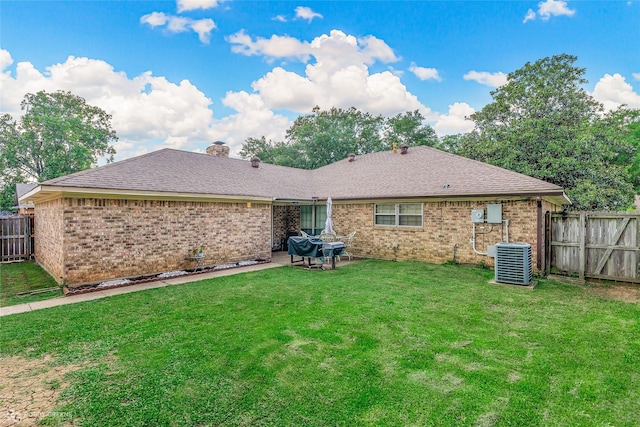 rear view of property featuring central AC unit, a chimney, fence, a yard, and brick siding