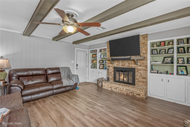 living room featuring built in shelves, visible vents, beam ceiling, and wood finished floors