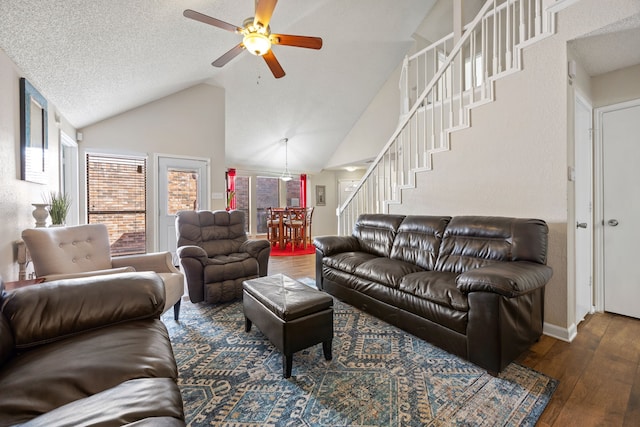 living area with a ceiling fan, hardwood / wood-style flooring, stairs, a textured ceiling, and high vaulted ceiling