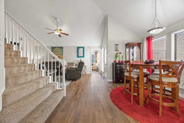 dining room featuring ceiling fan, high vaulted ceiling, baseboards, stairs, and wood-type flooring