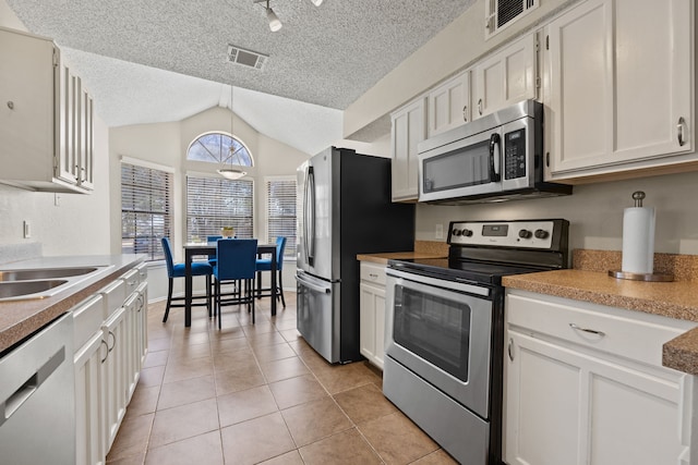 kitchen with appliances with stainless steel finishes, lofted ceiling, visible vents, and light tile patterned floors