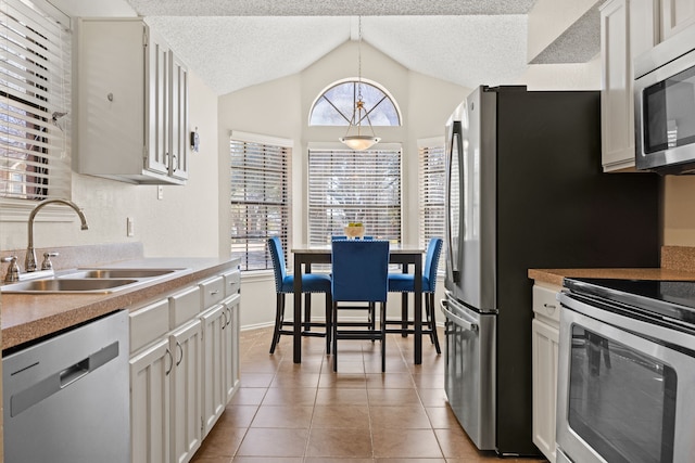 kitchen featuring light tile patterned floors, a textured ceiling, appliances with stainless steel finishes, and a sink