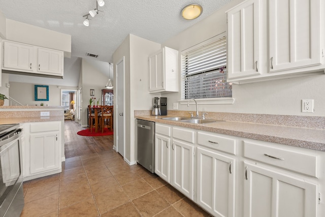 kitchen featuring appliances with stainless steel finishes, white cabinets, light countertops, and a sink