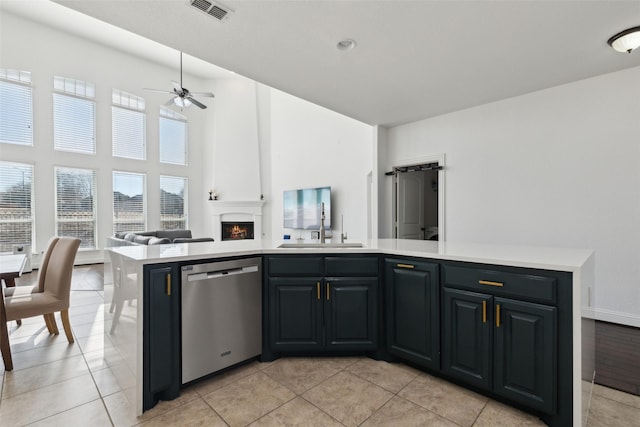 kitchen with visible vents, dishwasher, open floor plan, a fireplace, and a sink