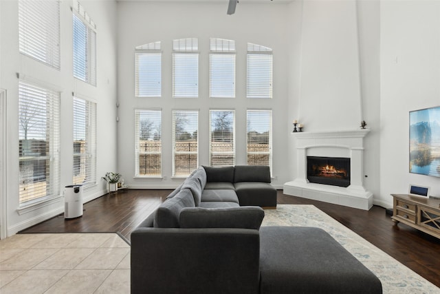 tiled living area with a fireplace, a towering ceiling, and baseboards