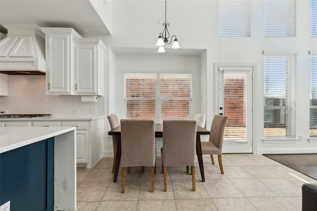 dining area with baseboards, a notable chandelier, and light tile patterned flooring