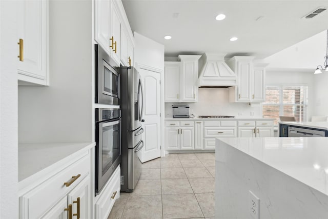 kitchen with light tile patterned floors, stainless steel appliances, visible vents, white cabinetry, and custom exhaust hood