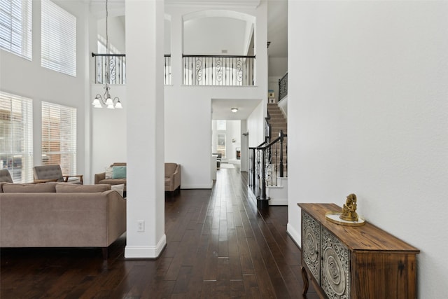 interior space featuring a chandelier, dark wood finished floors, baseboards, and stairs