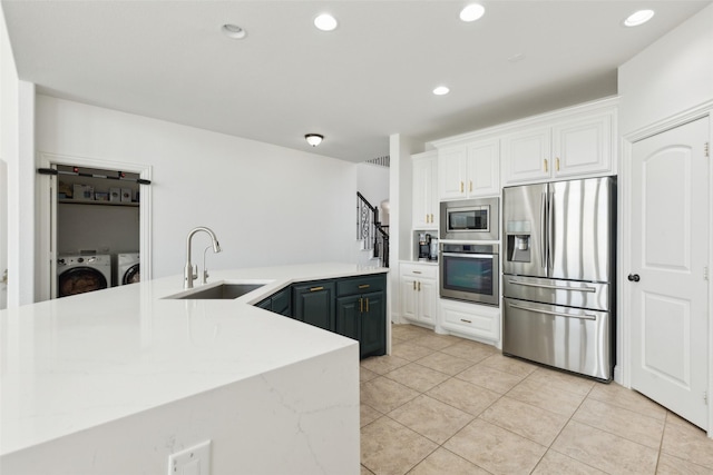 kitchen with recessed lighting, a sink, white cabinetry, appliances with stainless steel finishes, and washing machine and clothes dryer