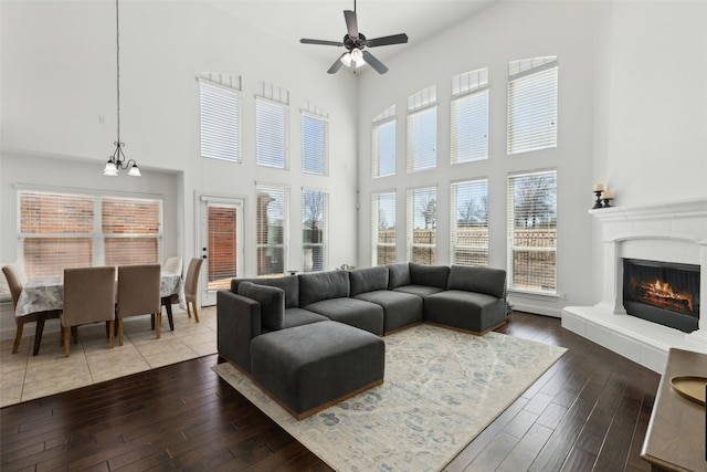 living area featuring a glass covered fireplace, hardwood / wood-style floors, and ceiling fan with notable chandelier