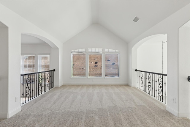 carpeted spare room featuring lofted ceiling and visible vents