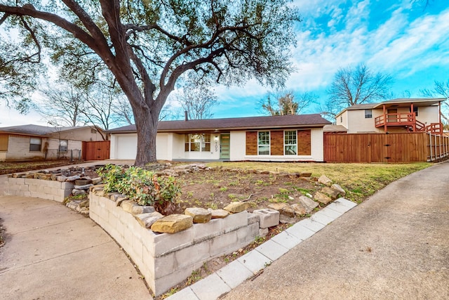 ranch-style home with a garage, driveway, brick siding, and fence